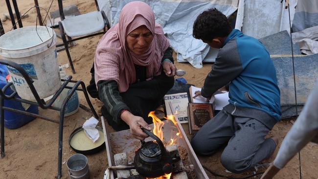 A displaced Palestinian burns pages of a book, collected from the destroyed Islamic University, to cook a meal in Gaza City. Picture: Omar Al-Qattaa / AFP