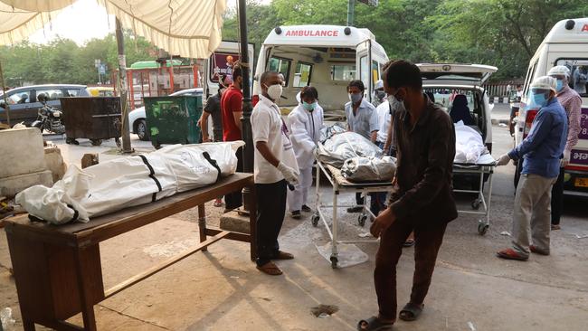 Healthcare workers and family members carry a body of a relative who died from coronavirus. Picture: Getty