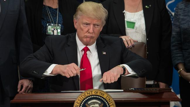 Donald Trump takes the cap off a pen to sign an executive order to start the Mexico border wall project at the Department of Homeland Security facility in Washington, DC, on January 25, 2017. Picture: Nicholas Kamm/AFP