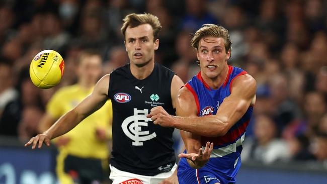 MELBOURNE.  24/03/2022.   AFL. Round 2.  Western Bulldogs vs Carlton at the Marvel Stadium .  Bulldog Roarke Smith clears by hand in front of Lochie OÃBrien of the Blues   . Photo by Michael Klein