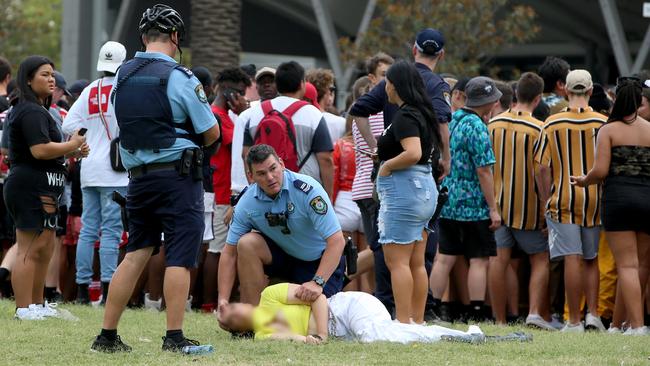 A police officer helps a distressed girl as others queue at the entrance to the Rolling Loud Festival at Sydney’s Olympic Park yesterday. Picture: Damian Shaw