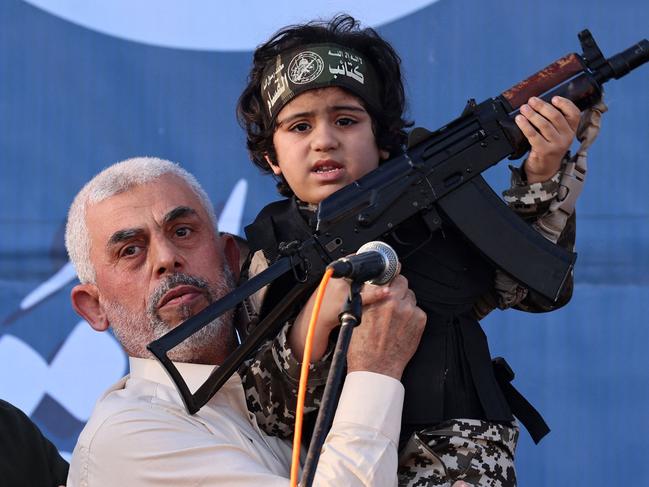 (FILES) Hamas leader Yahya Sinwar holds the child of an Al-Qassam Brigades fighter, who was killed in the recent fighting with Israel, with a Kalashnikov rifle in his hand during a rally in Gaza City on May 24, 2021. An Israeli security official told AFP on October 17, 2024 that the military was conducting a DNA test on a militant's body to confirm whether it was Hamas chief Yahya Sinwar. (Photo by Emmanuel DUNAND / AFP)