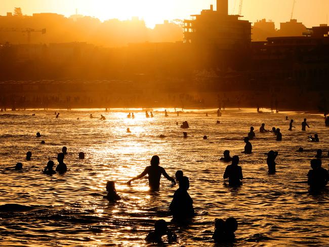 People pictured in the water at Sydney’s Bondi Beach as the sun goes down on another hot Autumn day. Picture: Damian Shaw