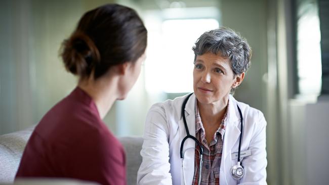 Shot of a compassionate doctor comforting a young woman in a hospital waiting room. File photo.