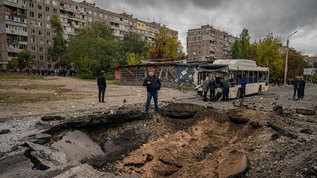 Investigators examine a crater and a damaged bus following a missile strike in Dnipro. Picture: AFP