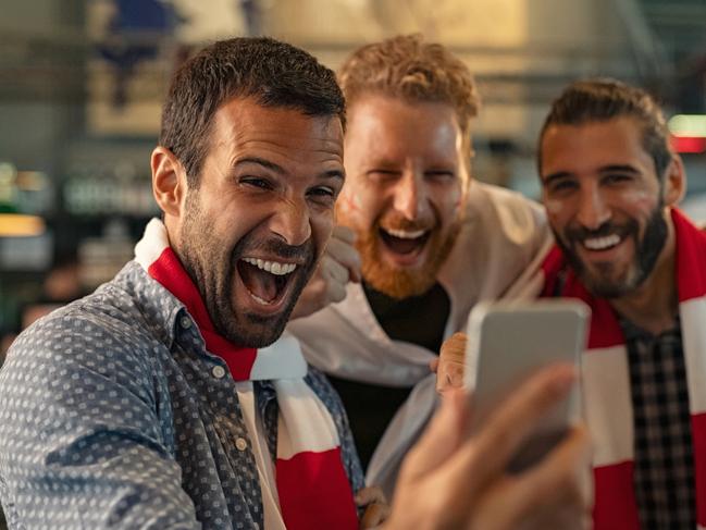 Excited men watching football in streaming on smartphone winning an online bet; generic gambling betting