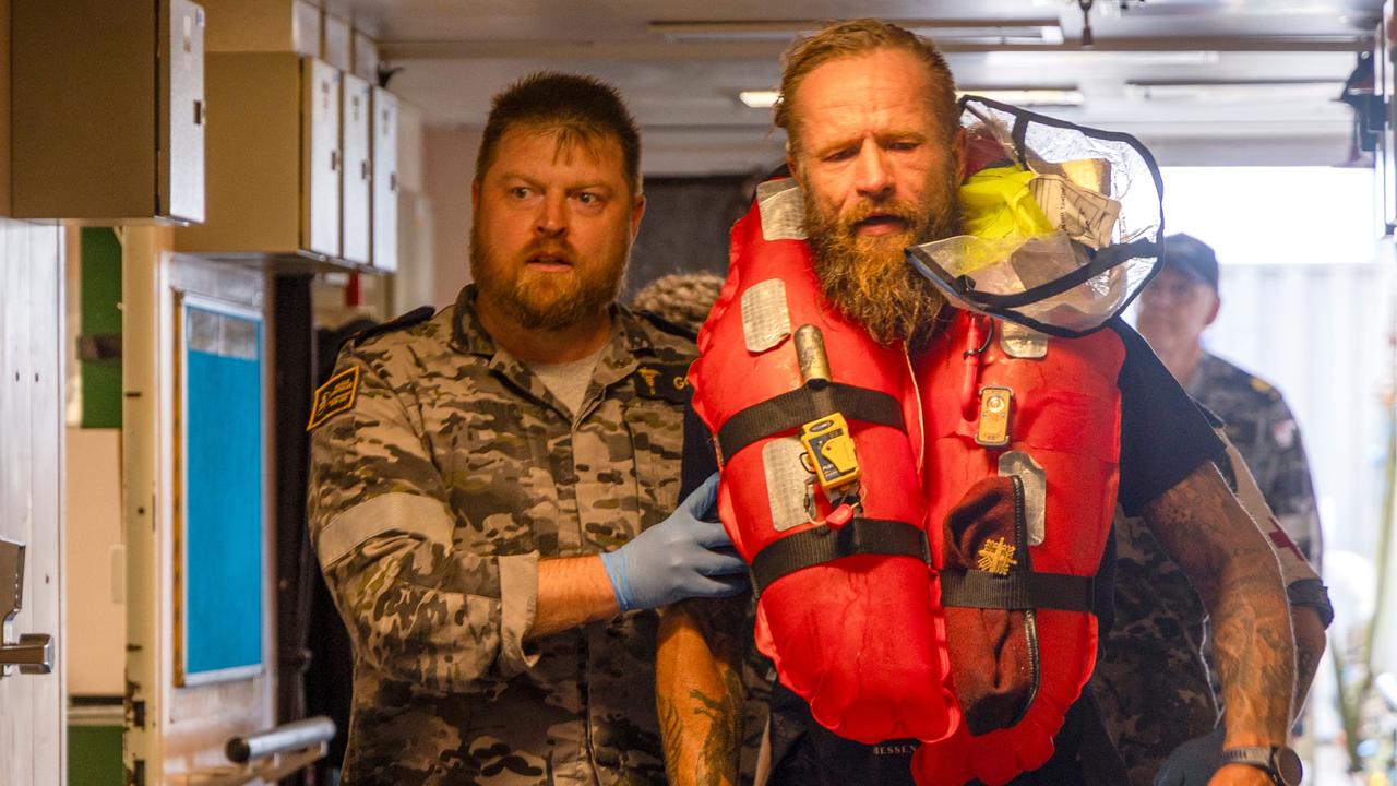 Chief Petty Officer Medic Peter Gough leads solo rowboat adventurer Aurimas Mockus to the ship's hospital on-board HMAS Choules. Picture: Royal Australian Navy