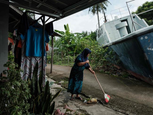 Syafriani, whose mother is still missing after the 2004 Indian Ocean tsunami, cleans in front of her house where two patrol boats washed ashore and remain preserved in Banda Aceh. Picture: AFP