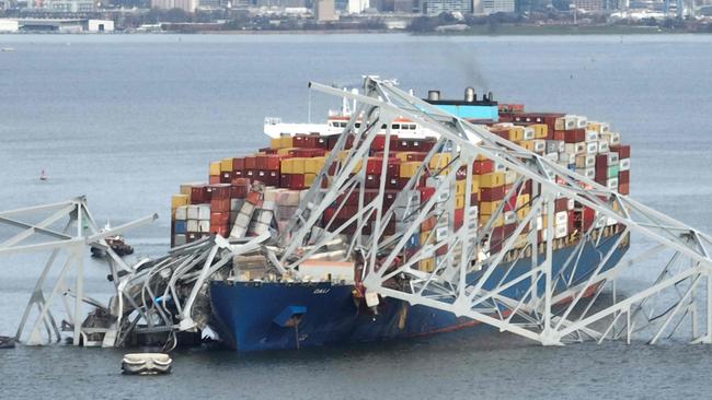 The steel frame of the Francis Scott Key Bridge sits on top of a container ship after the bridge collapsed. (Photo by Jim WATSON / AFP)