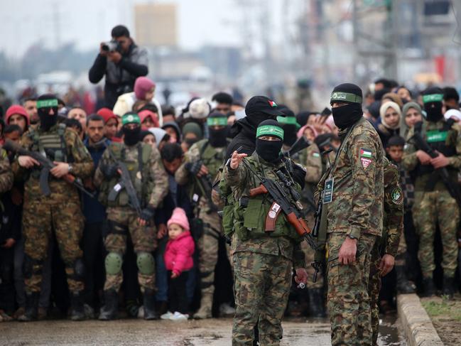 Palestinians and Hamas fighters shortly before the release three Israeli hostages as part of the seventh hostage-prisoner swap, in Nuseirat in the central Gaza Strip on February 22, 2025. Three more Israeli hostages were freed by Hamas militants at a ceremony in central Gaza on February 22 after two others were released in the southern part of the Palestinian territory. (Photo by Eyad BABA / AFP)