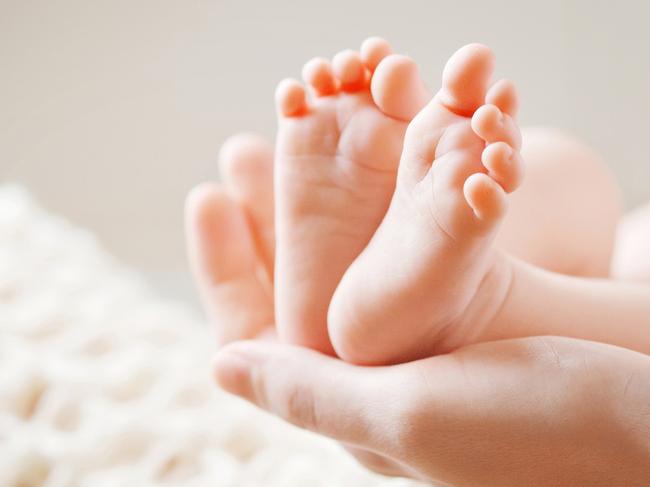 Baby feet in mother hands. Tiny Newborn Baby's feet on female Shaped hands closeup. Mom and her Child. Happy Family concept. Beautiful conceptual image of Maternity