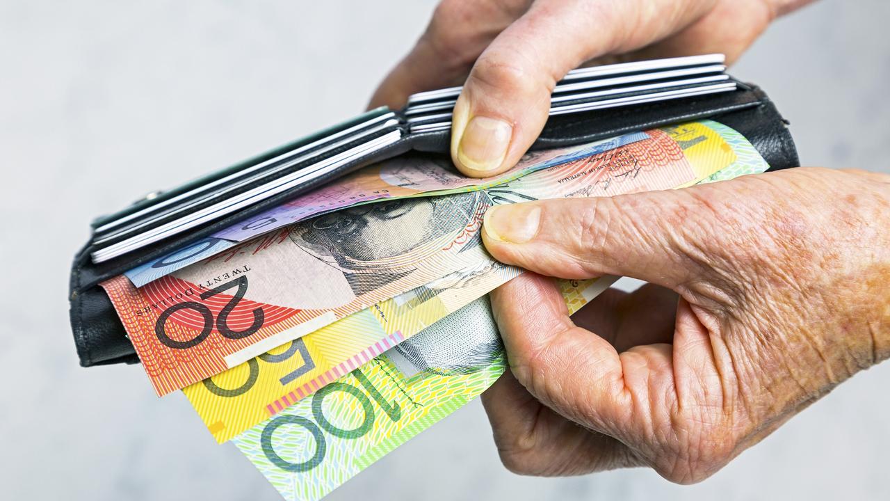 Close-up, senior female hands taking Australian banknotes (cash, currency) from purse containing many credit cards.  Horizontal, studio, copy space. Money generic