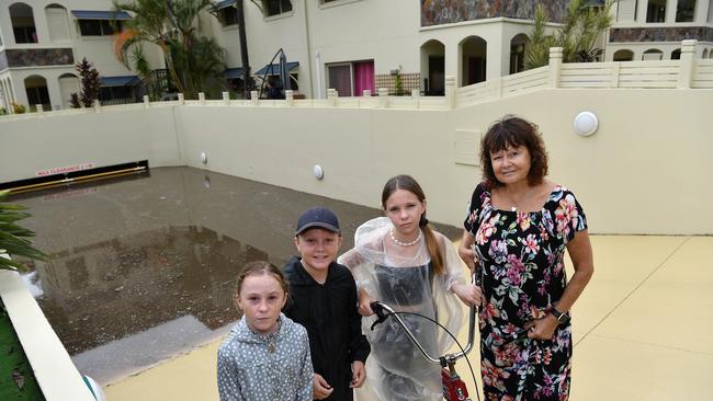 Izabelle Hamlyn, 9, Thomas Hamlyn, 11, Liv Froggatt, 14, and resident Kim Martin stand in front of the flooded car park. Picture: Patrick Woods / Sunshine Coast Daily.