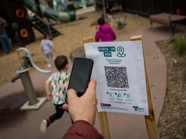 A parent uses the QR code check in at a playground in Brunswick. Picture: Darrian Traynor