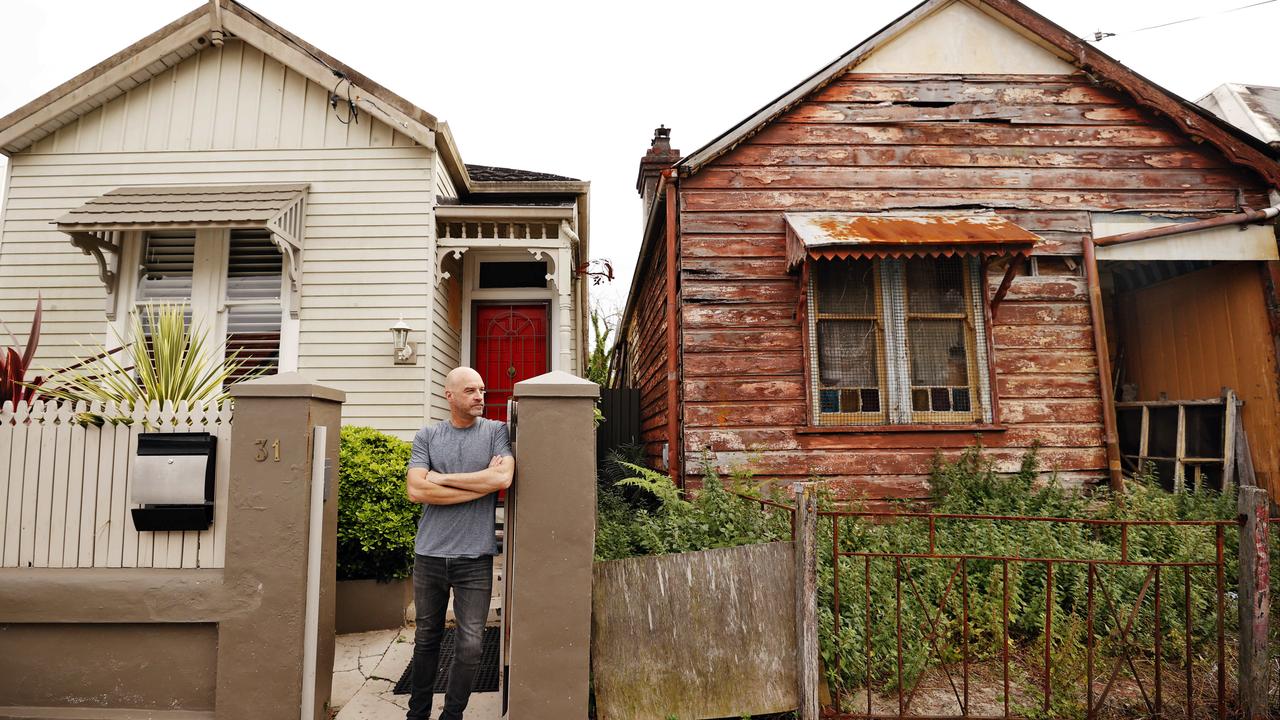 Jackson Pellow pictured out front of his Leichhardt house with the neighbouring home that has been abandoned for decades. Picture: Sam Ruttyn