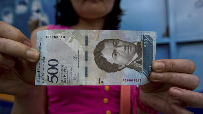 A bank customer shows a new bank note of 500 Bolivars outside a bank in Caracas, Venezuela. In figures released on January 8, Venezuela’s opposition-controlled legislature said inflation reached a staggering 2600 per cent last year. Picture: AP/Fernando Llano