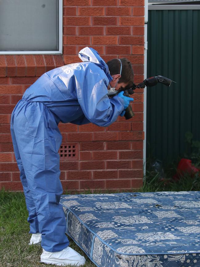 A forensics officer photographs a bed mattress. Picture: David Swift