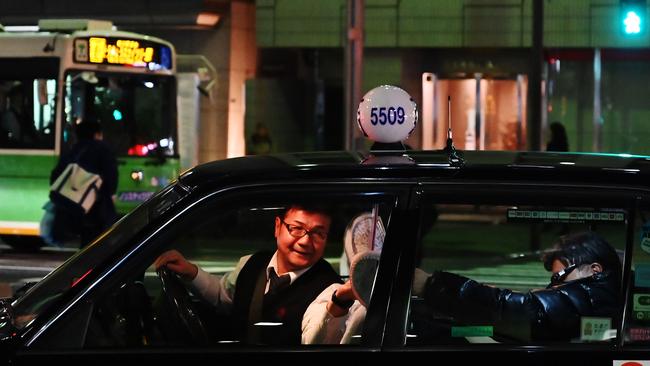 A passengers pays a taxi driver in Tokyo. Pic: Charly Triballeau