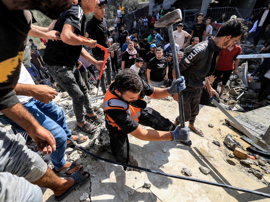 A Palestinian civil defence member uses a hammer to carve open a hole in the concrete surface of a building that was hit by Israeli bombardment in Khan Yunis in southern Gaza. Picture: AFP