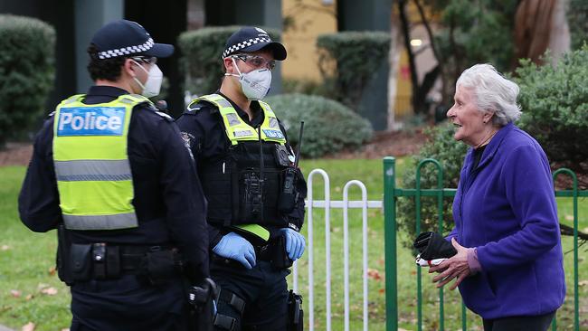 Police talk to a lady who left the public housing estate. Picture: Ian Currie