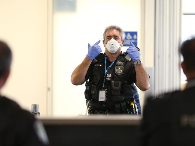 A police officer directs colleagues to don their masks before talking to a passenger who arrived to the Sunshine Coast from Melbourne this morning. Photo Lachie Millard