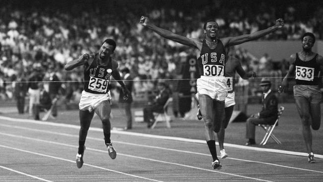 Tommie Smith throws his arms up in victory as he hits the tape to win gold in the men's 200m dash on October 16, 1968. Running, despite an injured leg muscle, he streaked past teammate John Carlos of San Jose (left), who placed third behind Australian Peter Norman (just behind Smith).