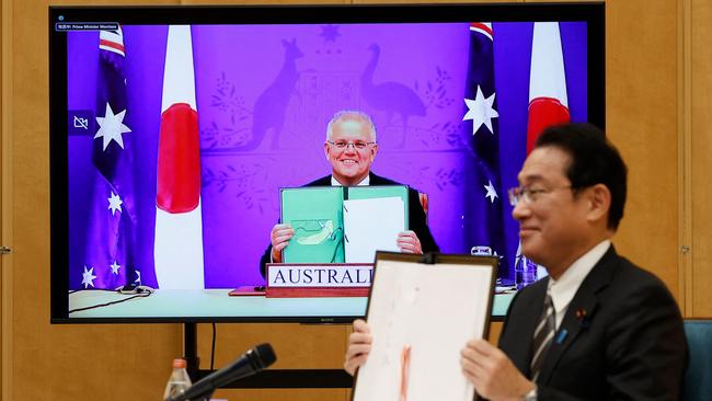 Japan's Prime Minister Fumio Kishida and Prime Minister Scott Morrison hold signed documents during their video signing ceremony of the bilateral reciprocal access agreement. Picture: Photo by ISSEI KATO / POOL / AFP.