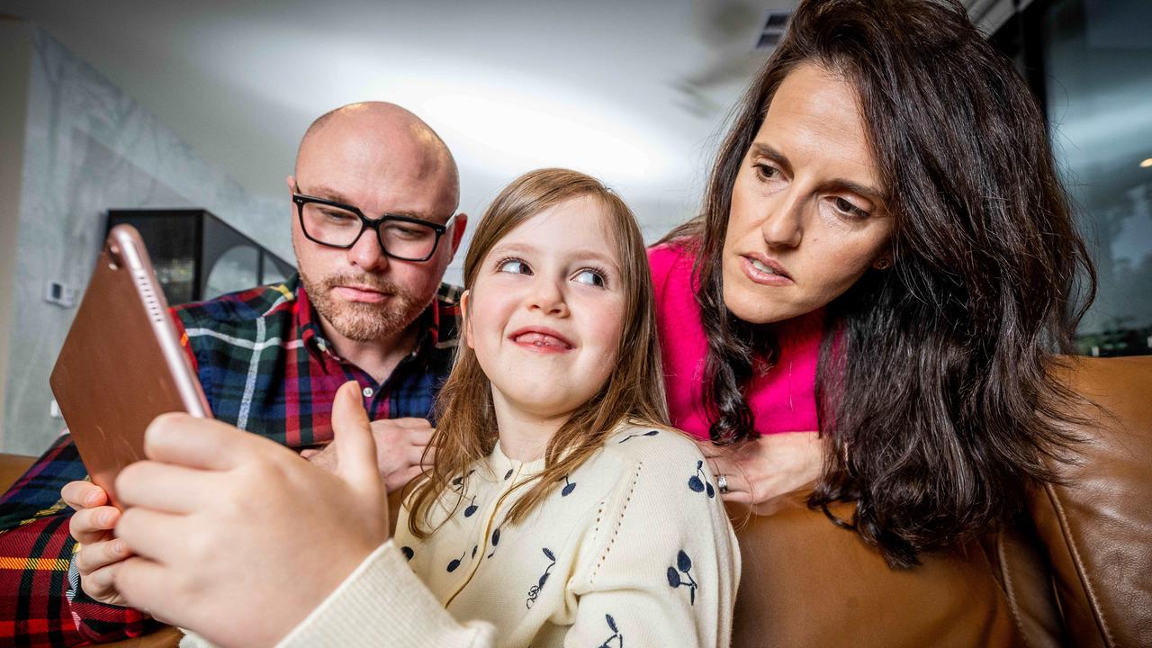 Damian Corney, Adele Corney and their daughter Alessia carefully choose apps for her iPad. Picture: Jake Nowakowski