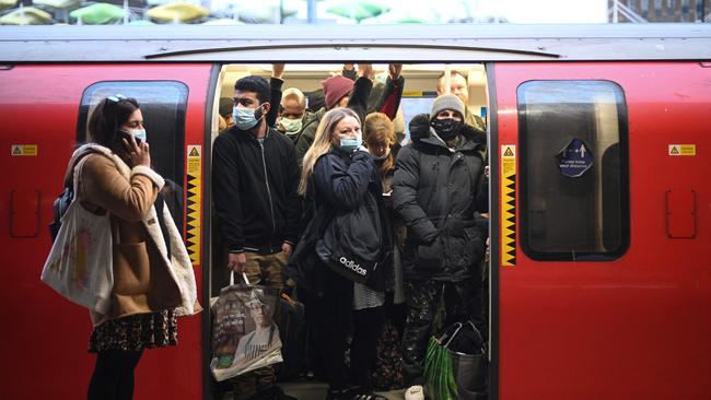 Commuters with and without face coverings ride a tube train at Stratford underground station in east London on December 1, 2021. - Britain will require all arriving passengers to isolate until they can show a negative PCR test against Covid-19 and is restoring a mandate to wear face masks in shops and public transport as part of its response to the new Omicron strain of Covid-19. (Photo by Daniel LEAL / AFP)