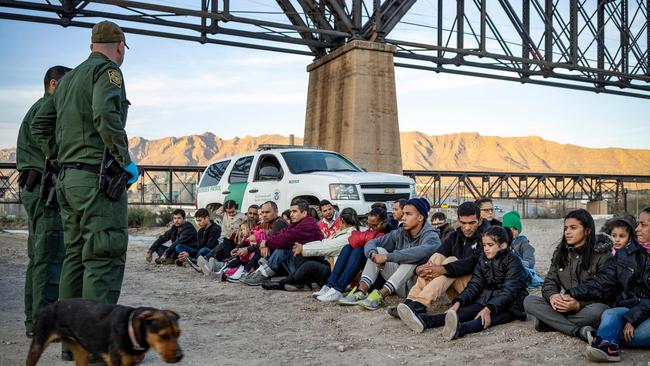 A group of about 30 Brazilian migrants, who had just crossed the border, sit on the ground near US Border Patrol agents. Picture: AFP