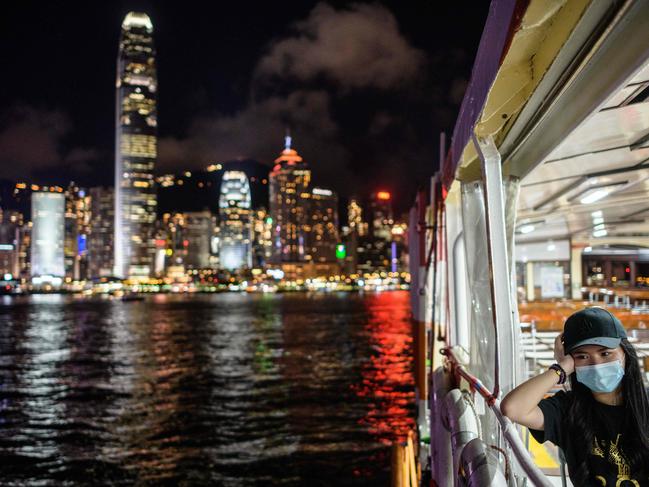 TOPSHOT - A woman wearing a face mask takes a Star Ferry in Victoria Harbour from Kowloon side to Hong Kong Island (back) on July 27, 2020. - Everyone in Hong Kong will have to wear masks in public from this week, authorities said on July 27, as they unveiled the city's toughest social distancing measures yet to combat a new wave of coronavirus infections. (Photo by ANTHONY WALLACE / AFP)