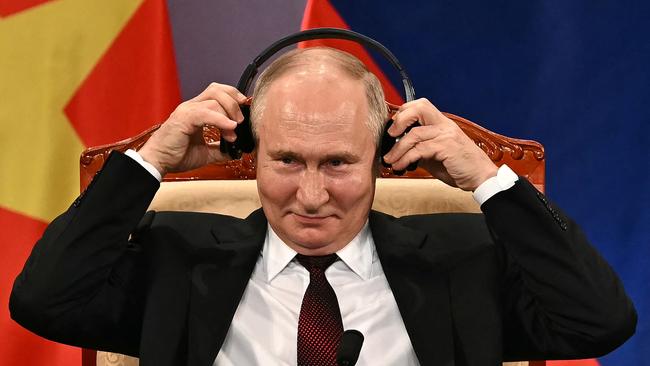 Vladimir Putin adjusts his headphones on stage during an event with Vietnam's President To Lam in Hanoi on Thursday. Picture: AFP