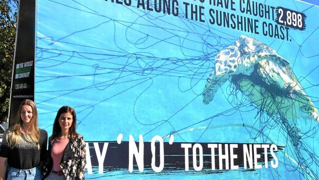 SEALIFE STAND: Hannah Tait and Jordan Sosnowski of Action for Dolphins with the confronting anti-shark net billboard in Noosa on Wednesday. Picture: Peter Gardiner