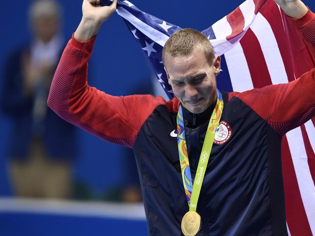 USA’s Caeleb Dressel cries while standing with his gold medal on the podium