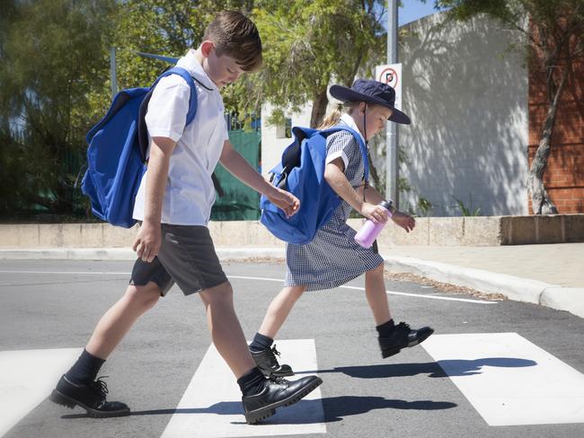 School children crossing the road safely at the cross walk. Australia