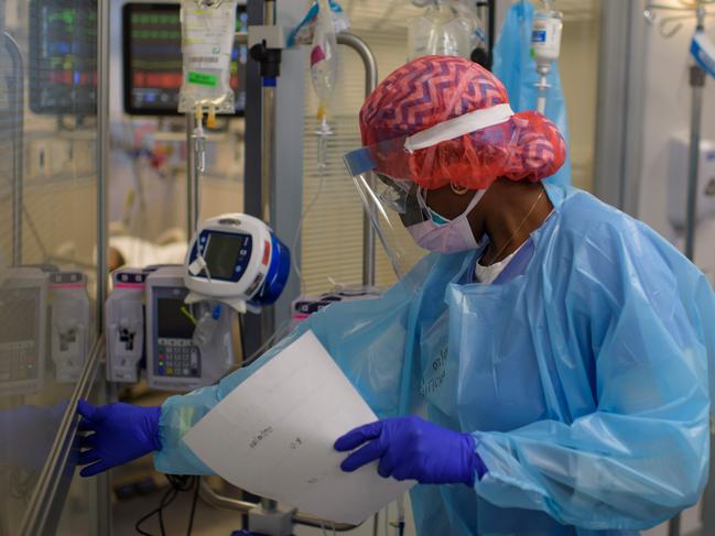 Registered Respiratory Therapist Niticia Mpanga walks into a Covid patientâs room in the ICU at Oakbend Medical Center in Richmond, Texas, on July 15, 2020. - The latest modeling projects the number of COVID-19 deaths in the US to increase further, even as one research team suggests the near-universal use of masks could save 40,000 lives between now and November (Photo by Mark Felix / AFP)