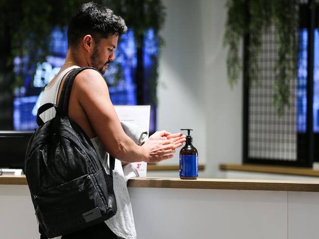 A Fitness First gym goer using hand sanitiser distributed around Fitness First George St on Saturday afternoon. Picture: Gaye Gerard