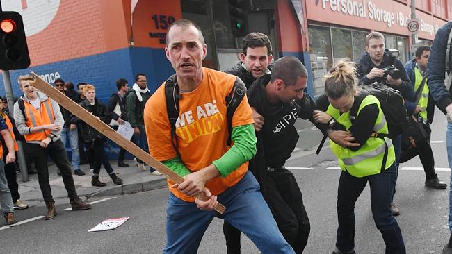 A protester brandishes a wooden club as fighting breaks out in the street. Picture: Jake Nowakowski