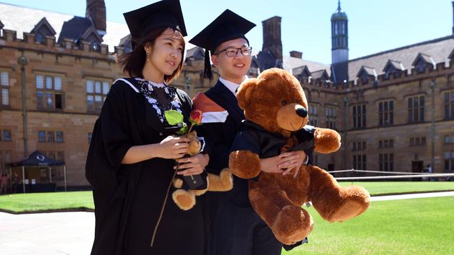 Students from China pose for family photos after graduating from a course in commerce at Sydney University. The government has committed to a range of measures aimed at ensuring foreigners do not “hop” between visas in order to stay working in Australia. Picture: AFP Photo/William West