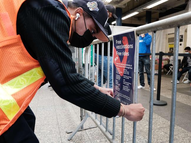 A worker puts up a sign for the COVID-19 vaccination shot at the Broadway Junction subway station in Brooklyn in New York City. Picture: Getty Images/AFP