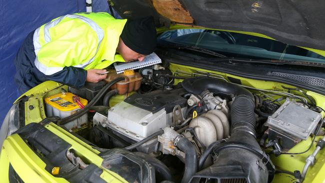 An officer inspects a car engine. Picture: Brendan Beckett