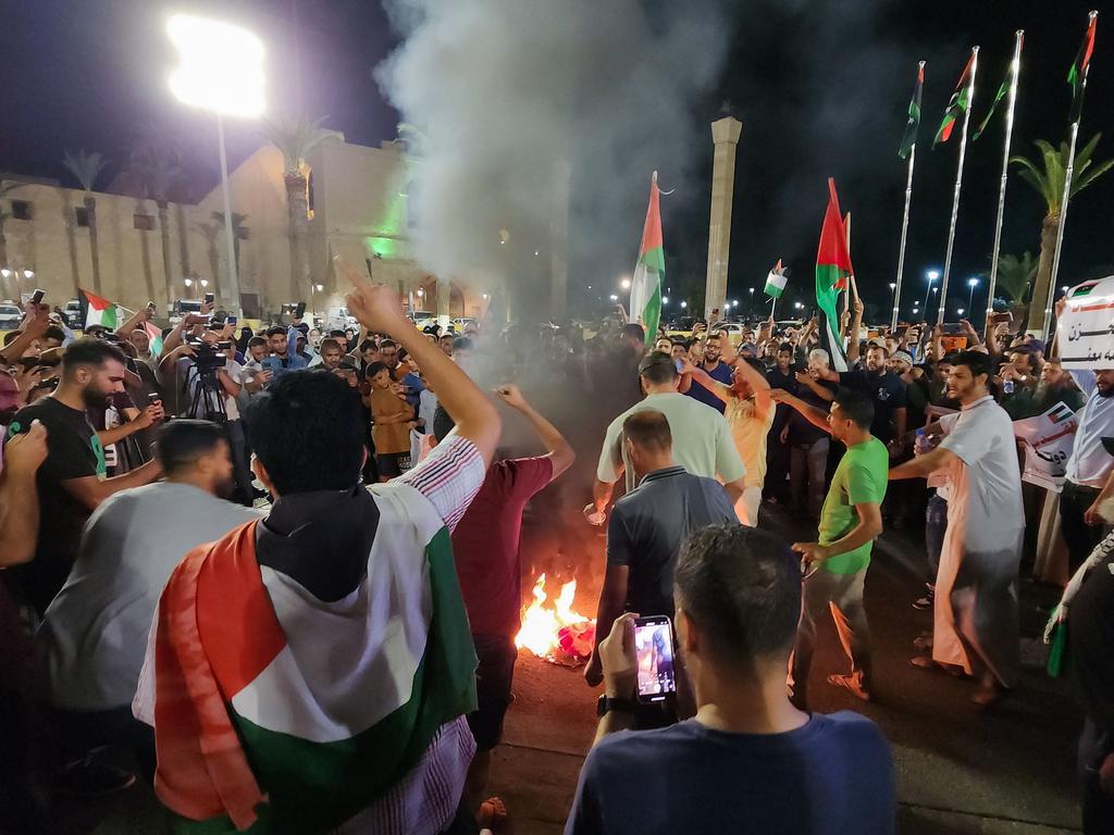 People burn a US flag during a protest in Libya's capital Tripoli late on October 17, 2023.