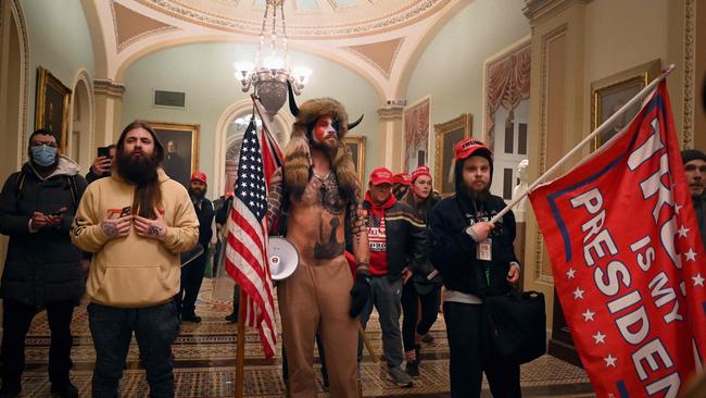 Supporters of US President Donald Trump, including member of the QAnon conspiracy group Jake Angeli, aka Yellowstone Wolf (C) and the QAnon Shaman, enter the US Capitol.