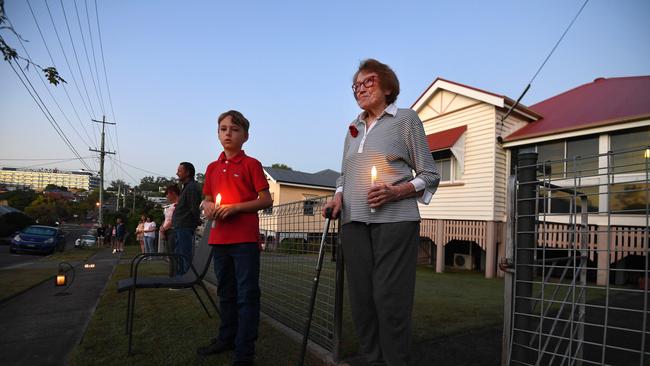 90 year-old Kathleen Callaghan and her neighbour Archer Bailey, 8, stand outside their homes at dawn to commemorate Anzac Day in Brisbane, Saturday, April 25, 2019. Anzac Day is a national day of remembrance to commemorate the service and sacrifice of Australian and New Zealand service men and women. Due to COVID-19 restrictions marches and commemorative services have been banned for the first time in more than a century. (AAP Image/Dan Peled) NO ARCHIVING