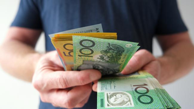 A man counting Australian dollar bills. A picture that describes buying, paying, handing out money, or showing money. Australian cash money generic