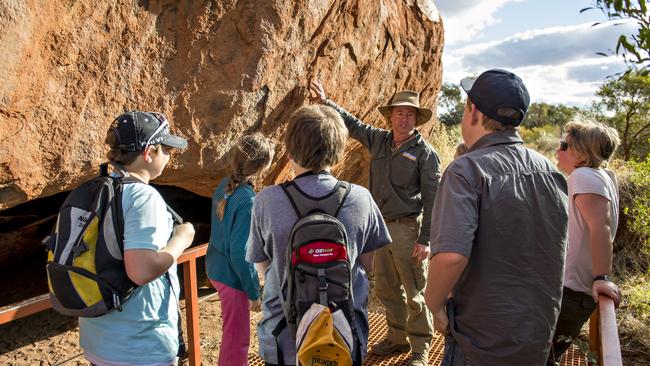 Visitors during a guided tour on the base walk around Uluru.<br /><br />One of the great natural wonders of the world, Uluru towers above the surrounding landscape. Uluru is not only a spectacular natural formation, but its a deeply spiritual place. You can feel a powerful presence the moment you first set eyes on it.