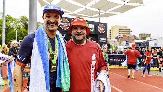 Tasmanian triathlete Tim Belstead is greeted by volunteer Tom Brown at the finish of the 70.3 Tasmania in Hobart on Sunday 4th February 2024. Picture: Linda Higginson