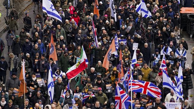 People hold placards and wave flags as they attend a march against anti-Semitism in London. Picture: AP