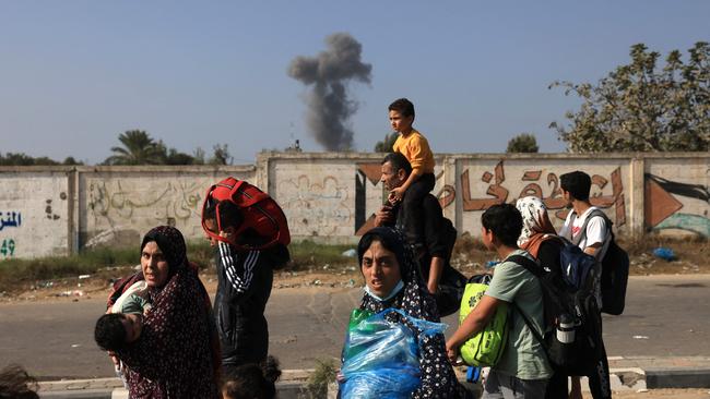 Smoke rises in the background as Palestinians families fleeing Gaza City and other parts of northern Gaza towards the southern areas. Picture: MAHMUD HAMS / AFP