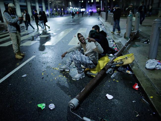 People sit on a broken traffic light while celebrating.